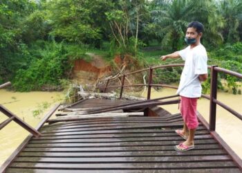 ABDUL Wahid Hasan menunjukkan jambatan besi yang rosak akibat banjir di Kampung Padang Toi, Sik semalam. – UTUSAN/NORLIA RAMLI