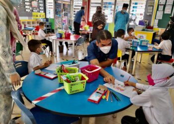 RADZI Jidin membantu seorang murid yang sedang menyiapkan tugasan mewarna ketika meninjau SK Semasih, Panchor di Muar. - UTUSAN/NUR ALINA HASSAN