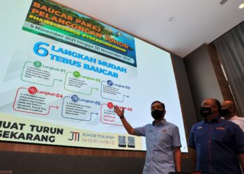 ONN Hafiz Ghazi (kiri) menerangkan proses penebusan Baucar Pakej Pelancongan Johor di Iskandar Puteri, Johor. - UTUSAN/RAJA JAAFAR ALI
