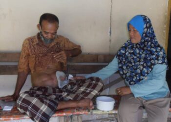 ZAUYAH Khalid membersihkan bahagian perut dan beg najis suaminya, Muhammad Zohir Ahmad di rumah mereka di Kampung Titi Teras, Yan, Kedah. – UTUSAN/OTHMAN YAHAYA