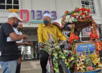 ARIFFIN Deraman (kanan) mencuba mengayuh beca selepas menyampaikan bantuan kepada 66 ejen pelancongan Terengganu di TD1303 di Kuala Terengganu. - UTUSAN/PUQTRA HAIRRY ROSLI