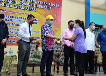 HAJIJI Noor (tiga kiri) menyampaikan bantuan wang ehsan kepada salah seorang mangsa yang terjejas banjir di Mukim Labak, Kinarut di Papar hari ini.
