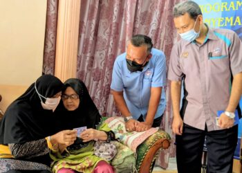 RUSLIN Jusoh (dua kanan) melihat Sehah  Alang Shafie (dua kiri) membelek MyKad baharu yang diterima wanita  berusia 98 tahun itu di Bukit Chandan, Kuala Kangsar hari ini.  - UTUSAN/MOHAMAD HAFIZI MOHD. SAID