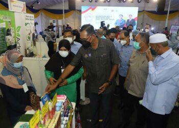 ROSOL Wahid (tengah) diberi penerangan mengenai produk yang dipamerkan oleh seorang peniaga yang menyertai Karnival Jualan Beli Barangan Malaysia sempena perasmian Kempen Beli Barangan Malaysia di Langkawi hari ini. - UTUSAN/NUR AMALINA AZMAN
