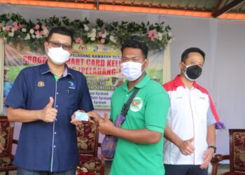 DZULFADLI Johan (kiri) menyampaikan Kad Pintar Keluarga Peladang kepada penerima kad itu, Mohd. Razif Baharom di PPK Bera di Bera, Pahang. - UTUSAN/SALEHUDIN MAT RASAD