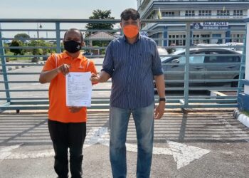 MOHD. Ikhmal Mohd Iskandar (kiri) dan Ahli Jawatankuasa Amanah Kawasan Lumut, Abdul Mutalib Zakaria bersama laporan polis yang dibuat di IPD Manjung hari ini. - UTUSAN/SHAMSUL KAMAL AMARUDIN