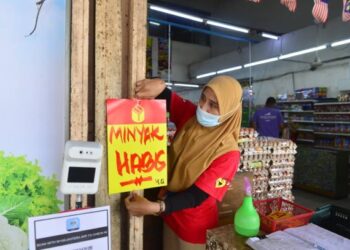 SEORANG pekerja pasar raya menampal pelekat minyak habis di Kuantan, Pahang. – UTUSAN/SHAIKH AHMAD RAZIF