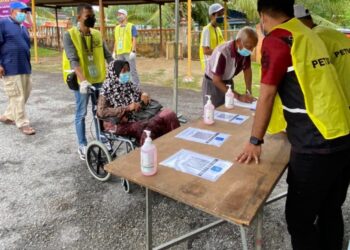 PETUGAS pusat mengundi membantu warga emas ke kaunter pendaftaran di SK Durian Daun, Lendu, Melaka hari ini.