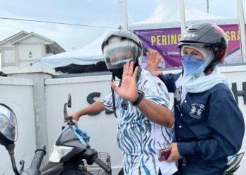 IDRIS Haron menunggang motosikal bersama isterinya ketika hadir ke SJKC Lih Jen untuk membuang undi. - UTUSAN/DIYANATUL ATIQAH ZAKARYA