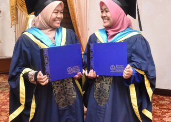 ADIK beradik kembar seiras, Norhidayati Misman (kiri) dan adiknya Norhidayani menerima ijazah pada Majlis Istiadat Konvokesyen UPSI Ke-22 di Tanjung Malim hari ini. - UTUSAN/IHSAN UPSI