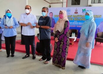 IZHAM Hashim (dua kiri) menyerahkan subsidi minyak petrol kepada seorang penerima di Kompleks LKIM Kuala Selangor, hari ini.