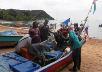 BEBERAPA nelayan memeriksa enjin bot sebelum turun ke laut di Telok Nipah, Pantai Merdeka, Kota Kuala Muda, Sungai Petani semalam. – UTUSAN/OTHMAN YAHAYA