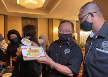 AHMAD Hamzah menunjukkan produk tauhu ikan patin selepas merasmikan Agroinvest Mardi 2021 di Hotel Hatten, Banda Hilir, Melaka. - UTUSAN/DIYANATUL ATIQAH ZAKARYA