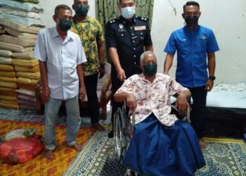 MAT Ariffin Mat Deris (berkerusi roda) bersama Azli Mohd. Noor (tengah) dan Amir Marwan Abu Kassim (belakang, kanan) ketika penyampaian kerusi roda dan makanan sumbangan Abdul Rahman Mohamad di Kampung Tanjung Buloh di Lipis, Pahang. – FOTO/HARIS FADILAH AHMAD