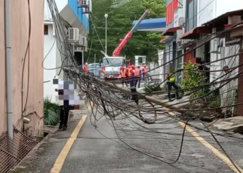 TIANG elektrik yang tumbang dipercayai tersangkut ketika sebuah treler yang melalui Jalan Ahmad Boestaman, Slim River semalam. - UTUSAN/IHSAN PDRM