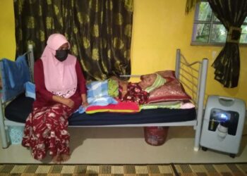 KHATIJAH Che Wain (duduk) menjaga ibunya, Salmah Husin (berbaring) yang cuma bernafas menerusi peralatan oksigen elektrik di Felda Sungai Tekam di Jerantut, Pahang. - UTUSAN/HARIS FADILAH AHMAD