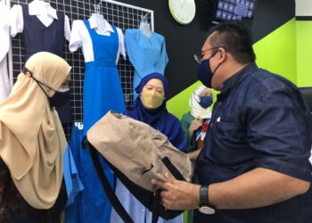 PENGARAH Urusan Canggih Sutera Sdn.Bhd., Rozamir Zulkifli (kanan) menunjukkan beg keluaran Canggih Sutera Sdn. Bhd, kepada  Azizah Mohd. Dun (tengah) pada pelancaran program Canggih Go dan pembukaan outlet syarikat itu di Ampang Baru di Ipoh hari ini. -  UTUSAN/LIYANA RAMLI