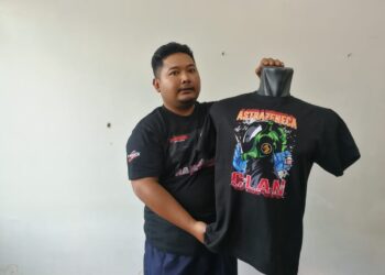 MOHD. Hafiz Almuhaimi Mohd. Halim  menunjukkan baju-T yang dijualnya menerusi platform e-dagang ketika ditemui di Dungun, hari ini. - UTUSAN/NIK NUR IZZATUL HAZWANI NIK ADNAN