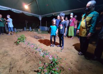MUHAMMAD Afiq Muhammad Anas dan adiknya, Siti Nur Alya Adriana berada di sisi kubur ibu bapa mereka,  Muhammad Anas Awang serta Siti Hafissah Zamri yang selamat dikebumikan dalam satu liang di Tanah Perkuburan Kampung Kuala Bakong, Kuala Ketil, Baling malam ini. - UTUSAN/NUR SYAZWANA MANSOR