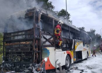 ANGGOTA bomba memadamkan kebakaran sebuah bas yang membawa 45 orang pekerja kilang dalam kejadian di Jalan Seremban-Kuala Pilah dekat Bukit Putus, tengah hari tadi.- GAMBAR/IHSAN BOMBA