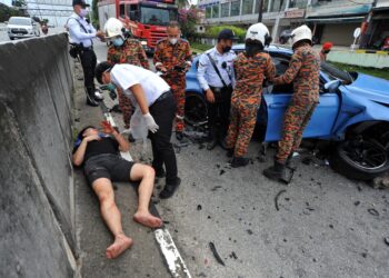 ANGGOTA paramedik membantu Sean Ho Jing Rong yang cedera dalam kemalangan di Lebuhraya Lingkaran Dalam (EDL) berhadapan menara Majlis Bandaraya Johor Bahru (MBJB),    Johor Bahru, semalam. - UTUSAN/RAJA JAAFAR ALI