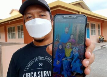 AZIZUL Mahrani menunjukkan gambar arwah abangnya bersama keluarga yang meninggal dunia pagi tadi akibat kecederaan ketika operasi pemadaman di sebuah kilang di Segamat, Johor. - UTUSAN/FARAHWAHIDA AHMAD