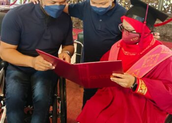 NORISAH Bahrom bersama suaminya, Abu Samah Borhan dan anak mereka, Adam Daniel melihat skrol Ijazah Sarjana Muda Sains Komputer dalam Majlis Konvokesyen ke-64 UTM di Skudai, Johor Bahru. -UTUSAN/BAZLAN IBRAHIM