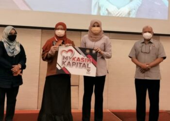 RINA Harun (dua kanan) menyampaikan geran bantuan MyKasih Kapital kepada salah seorang penerima di Kota Kinabalu hari ini.