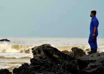 SEORANG anggota APM meninjau kawasan pencarian mangsa bot karam di perairan Tanjung Balau di Kota Tinggi, Johor. -UTUSAN/RAJA JAAFAR ALI