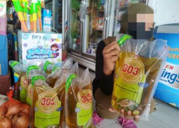 SEORANG pekerja menunjukkan minyak masak peket bersubsidi yang dijual di sebuah kedai runcit di Jeli, Kelantan.  - UTUSAN/ZULHANIFA SIDEK