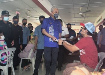 ISMAIL Sabri Yaakob (tengah) menyampaikan sumbangan kepada mangsa banjir ketika hadir di PPS SK Gangsa, Durian Tunggal, Melaka. - UTUSAN/RASUL AZLI SAMAD