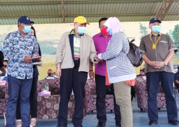 HAJIJI Noor (dua kiri) menyampaikan Bantuan Wang Ihsan kepada salah seorang mangsa banjir di Kota Marudu hari ini.