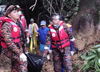PASUKAN bomba mengangkat mayat mangsa lemas yang ditemukan di sungai berhampiran Ladang Farminggo Sugut, hari ini. - IHSAN BOMBA
