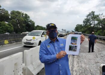 MOHD. Zolkafly Harun menunjukkan gambar  mendapan tanah di susur keluar Jalan Kuala Kangsar ke Meru yang ditutup satu lorong di Ipoh hari ini. - UTUSAN