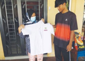 UMI Khalsom Murad menunjukkan pakaian sekolah lama yang akan dipakai Amirul Danish (kanan), pada sesi persekolahan Isnin ini di rumahnya di Pangsapuri Andorra, Taman Sri Muda, Seksyen 25 di Shah Alam Selangor.