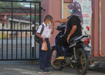 SEORANG murid bersalaman sebelum memulakan hari pertama persekolahan di Sekolah Kebangsaan Padang Mengkuang di Marang, hari ini. - UTUSAN/PUQTRA HAIRRY ROSLI