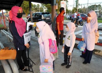 TIGA murid beratur untuk mengimbas suhu sebelum memasuki sekolah pada sesi persekolahan penggal ketiga di SK Sri Melati, Johor Bahru. - UTUSAN/RAJA JAAFAR ALI