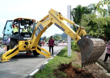 SAARANI Mohamad (tengah) mengendalikan jengkaut ketika pecah tanah projek naik taraf sebahagian Jalan Tambun di Ipoh hari ini. - UTUSAN/ZULFACHRI ZULKIFLI