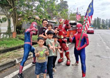 KANAK-KANAK tidak melepaskan peluang bergambar bersama adiwira pati Teh Ais Avenger berhampiran bulatan utama Padang Besar, Perlis.- UTUSAN/SYED AZLAN SAYID HIZAR