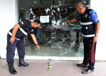 ANGGOTA Forensik PDRM menunjukkan kesan retak pada cermin sebuah bank akibat cubaan memecahkan oleh seorang lelaki di Bandar Bukit Tinggi, Klang, Selangor.