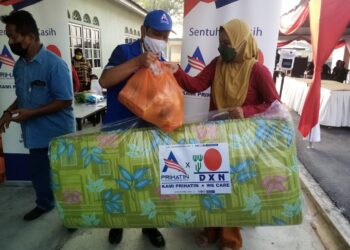 MOHD. Aizuddin Ghazali (tengah) menyampaikan sumbangan kepada salah seorang mangsa banjir di balai raya Kampung Bukit Lanchong, Shah Alam, Selangor. - UTUSAN / MOHAMAD NAUFAL MOHAMAD IDRIS