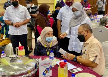WAN ROSDY Wan Ismail (kanan) menyampaikan Kad Kesihatan Warga Emas Pahang kepada seorang penerima pada majlis pelancaran inisiatif kad itu di Dewan Jubli Sultan Haji Ahmad Shah di Rompin, Pahang.