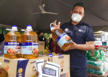 MOHD. RIDZUAN Ab. Ghapar menunjukkan minyak masak yang dipek dalam botol bersaiz lima kilogram (kg) yang dijual pada harga lebih rendah daripada harga pasaran menerusi PJKM di pekarangan Masjid At-Taqwa, Butterworth, Pulau Pinang hari ini.