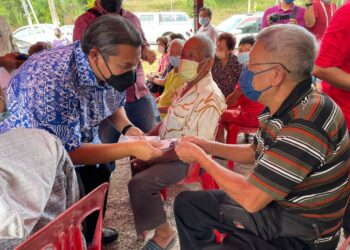 RAIS Yasin (kiri) menyampaikan sumbangan Tahun Baharu Cina kepada seorang penduduk di Tanjung Minyak, Melaka. - UTUSAN/DIYANATUL ATIQAH ZAKARYA
