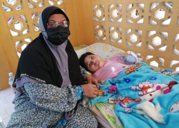 NIK Zatifah Nik Yusof bersyukur Junaidah Sulaiman yang lumpuh sejak kecil terselamat dalam kebakaran tujuh rumah di Taman Islam Kampung Bakau Tinggi, Chukai di Kemaman, hari ini. - UTUSAN/NIK NUR IZZATUL HAZWANI NIK ADNAN