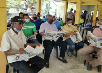 ARMISHAH Siraj (tengah) bersama beberapa penduduk membaca akhbar Utusan Malaysia pada program bantuan minyak diesel kepada nelayan di Jeti Pendaratan(LKIM Sungai Chenang, Langkawi  baru-baru ini. –  UTUSAN/NUR AMALINA AZMAN