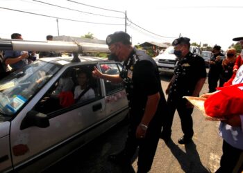SHAFIEN Mamat mengagihkan limau kepada pengguna jalan raya ketika melancarkan Op Selamat Tahun Baharu Cina di Tunjong, Kota Bharu Kelantan di sini hari ini. - UTUSAN/ZULHANIFA SIDEK