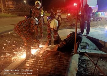 ANGGOTA bomba menggunakan peralatan khas bagi mengeluarkan kaki mangsa yang tersepit pada jeriji longkat di Kampung Selat dekat Parit semalam. - UTUSAN/HSAN JBPM PERAK