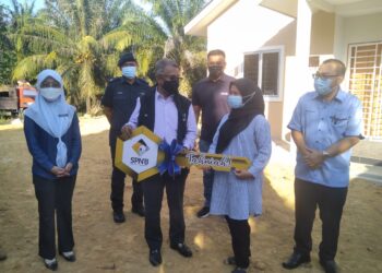 ISMAIL Abd. Muttalib (depan, kiri) menyampaikan replika kunci Rumah Mesra Rakyat kepada Nazatul Syuhada Puat Lottfi (kanan) di Kampung Batu Leja di Jerantut, Pahang. - UTUSAN/HARIS FADILAH AHMAD
