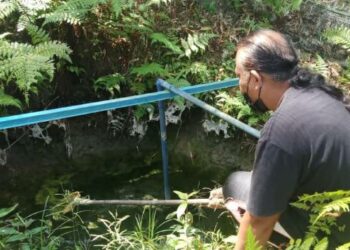 AHMAD Nasir Hamzah membersihkan daun-daun yang gugur ke dalam perigi lama berdekatan rumahnya di Kampung Bendang Darat, Bongor, Baling semalam. – UTUSAN/NORLIA RAMLI